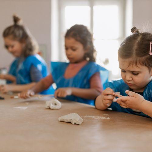 Children creating with pottery at the table.