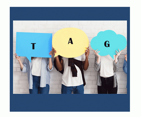 Teens standing together in front of a white wall with each holding a letter on paper spelling T A G  which stands for Teen Advisory Group.