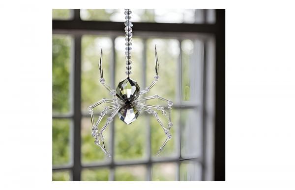 A crystal beaded spider hanging in front of window.